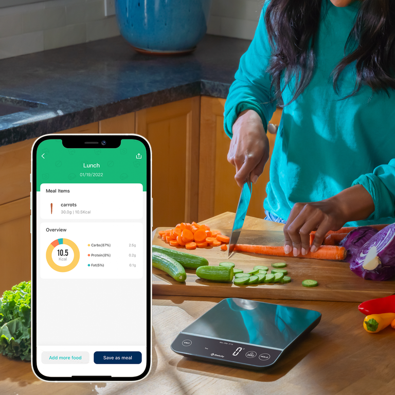 Etekcity Luminary™ Smart Nutrition Scale next to vegetables being chopped with nutrition facts on the VeSync app