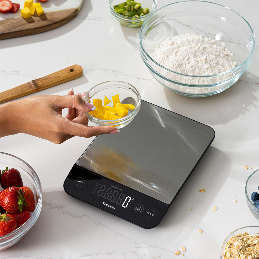Etekcity Luminary™ Kitchen Scale on a counter with bowl of ingredients around it 